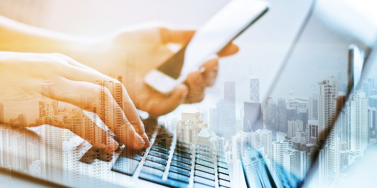 Double exposure of woman's hands using laptop and mobile phone a